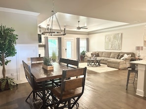 A spacious living area with a dining table, sofas, and a chandelier. - Spacious One Level Ranch Style Luxury Townhouse (Huntsville)