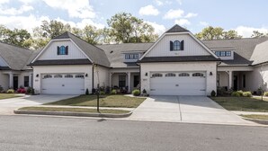 A suburban two-story house with a garage, a front porch, and a well-maintained lawn.