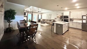 A spacious kitchen with a dining area, a living room, and a ceiling fan.