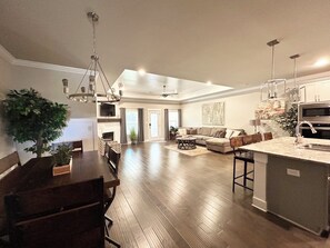 A spacious living area with a dining table, sofas, and a kitchen area with a large island. - Spacious One Level Ranch Style Luxury Townhouse (Huntsville)