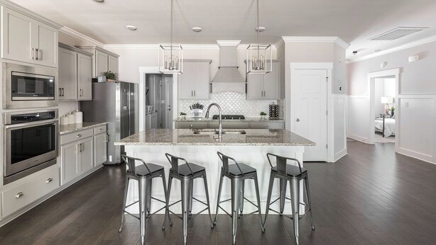 A modern kitchen with stainless steel appliances, a central island with bar stools, and pendant lighting.