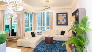 A modern living room with a sofa, coffee table, and a large window with curtains. - bnbme | Al Murjan Tower | 2 BDR (Dubai)