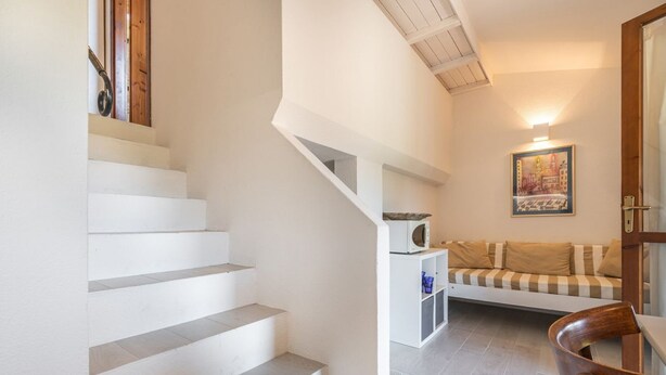A staircase leading to a living area with a sofa and a microwave on a small table. - Porto luna 24 - Selene (Villasimius)