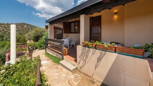 A modern house with a covered patio, outdoor furniture, and potted plants. - Porto luna 24 - Selene (Villasimius)