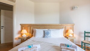 A neatly made bed with white linens and two pillows, flanked by bedside lamps on wooden nightstands. - Casa Perla - Domus de Maria (Domus De Maria)