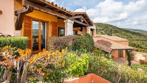 A Mediterranean-style villa with a terracotta roof, wooden shutters, and a garden with various plants and a pergola. - Casa Perla - Domus de Maria (Domus De Maria)