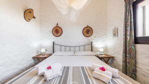 Ein geräumiges Schlafzimmer mit einem großen Bett, zwei Nachttischen, einem Baldachin und Blick ins Freie.