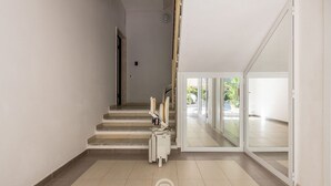 A hallway with a staircase leading to a glass door entrance. - Al Parco Studios - Studio Botticelli (Cagliari)