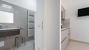A modern bathroom with a large mirror, a towel rack, and a sink. - Al Parco Studios - Studio Botticelli (Cagliari)