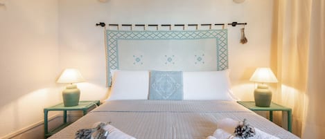Habitación de hotel con una cama, dos mesitas de noche, dos lámparas y cabecera con un diseño decorativo.