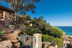 A coastal property with a stone staircase, a metal gate, and a view of the sea.