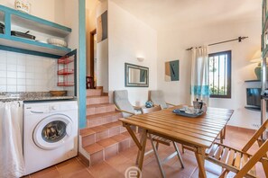 Un espace buanderie comprenant un lave-linge, une table en bois avec des chaises et un escalier.
