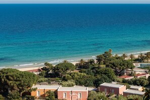 A coastal area with buildings, a beach, and palm trees. - Casa Belvedere: Paradise in Costa Rei (Muravera)