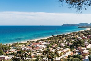 A coastal residential area with houses, a beach, and a clear view of the sea.