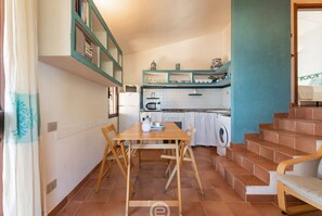 A compact kitchen with a dining table, chairs, and a washing machine.
