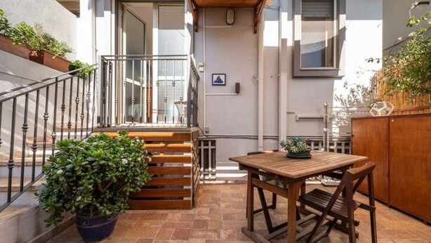 Un espace patio avec une table et des chaises en bois, une plante en pot et un banc en bois.