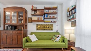 Un salon avec un canapé vert, des meubles en bois et des étagères.