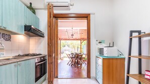 A kitchen with teal cabinets, a microwave, and a dining area visible through an open door. - Grace's House: Your Oasis of Peace in Villasimius (Villasimius)