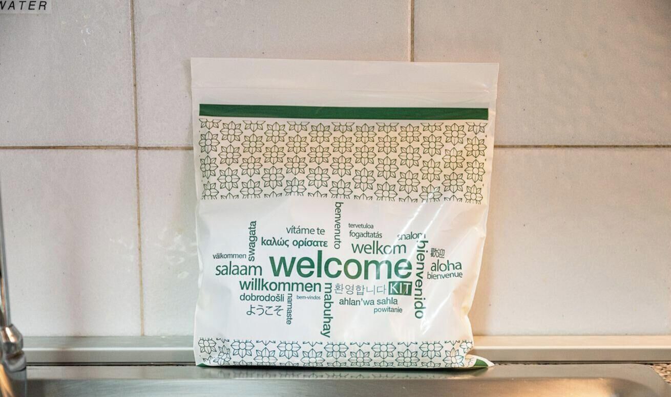 Een tas met welkomstgeschenken en meertalige begroetingen.