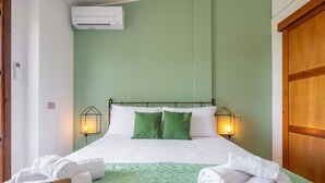 A hotel room with a bed, green walls, two bedside lamps, and a wooden wardrobe. - Grace's House: Your Oasis of Peace in Villasimius (Villasimius)