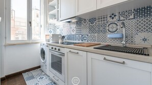 A kitchen with a washing machine, oven, and a tiled backsplash.