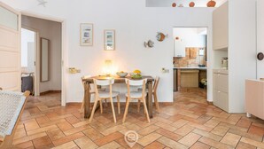 A dining area with a table and chairs, a kitchen in the background, and a star decoration on the wall. - Casa Flamingo - Next to the sea (Santa Margherita di Pula)