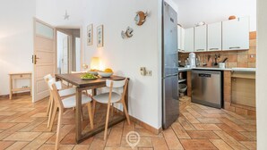 A compact kitchen with a dining area, featuring a refrigerator, stove, and a small sink. - Casa Flamingo - Next to the sea (Santa Margherita di Pula)