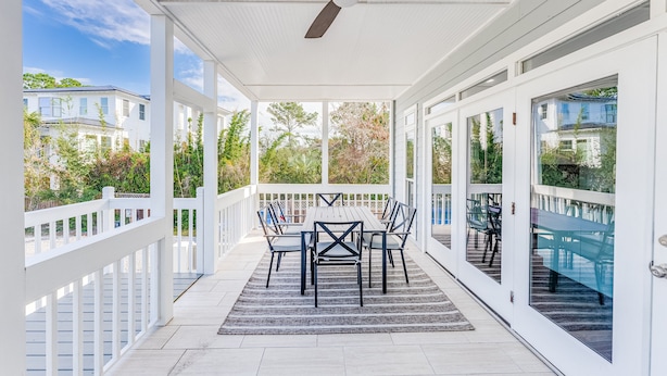A covered patio with a table and chairs, large windows, and a ceiling fan. - Luxury Beach House, Private Pool & Jacuzzi, Ocean Views by Tybee Cottages (Tybee Island)