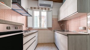 A compact kitchen with a gas stove, a sink, and a window with blinds.