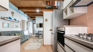 A modern kitchen with a built-in oven, a dining area with a table and chairs, and a living area with a sofa and decorative items on the wall.