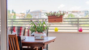 Un balcone con un tavolo in legno, un cuscino a quadri e una pianta fiorita in vaso.