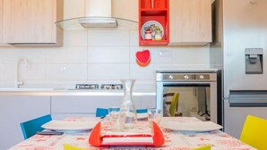 Una cucina moderna con mobili in legno, un frigorifero in acciaio inossidabile e uno scaffale rosso con oggetti da cucina.