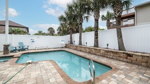 A swimming pool with a brick border, surrounded by a white fence, palm trees, and outdoor furniture. - Amazing Beachside Pool Home 5 Bedrooms - Summer Days Cooler NIghts (Wilbur by the Sea)