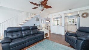 A modern living room with a dark leather sofa, a white side table, and a blue patterned rug. - Amazing Beachside Pool Home 5 Bedrooms - Summer Days Cooler NIghts (Wilbur by the Sea)