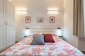 Een slaapkamer met een bed, twee kussens, een nachtkastje en drie ingelijste foto’s aan de muur.