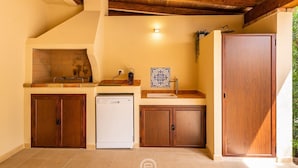 Una cucina compatta con lavastoviglie, mobili in legno, lavello e schienale decorato con piastrelle.