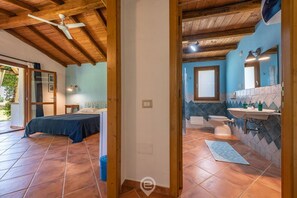 Ein Schlafzimmer mit einem Bett, einem Deckenventilator und Blick ins Freie.