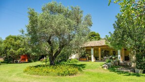 A villa with a tiled roof, surrounded by lush greenery and a well-maintained lawn.