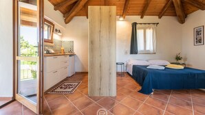 Ein Schlafzimmer mit einem Bett, einem Nachttisch, einem Fenster mit Vorhängen und einer Holzbalkendecke.