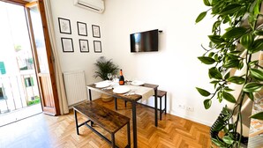 A dining area with a wooden table set for two, a potted plant, and a mounted TV on the wall. - Colosseum ★★★★★ - Rooftop with HOT jacuzzi and Skyline of Rome (Roma)