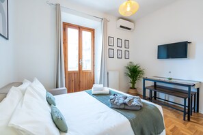 A bedroom with a bed, a desk, a TV, and a window with curtains. - Colosseum ★★★★★ - Rooftop with HOT jacuzzi and Skyline of Rome (Roma)