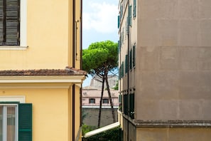 A narrow street with buildings on either side, a tree in the middle, and a clear sky. - Colosseum ★★★★★ - Rooftop with HOT jacuzzi and Skyline of Rome (Roma)