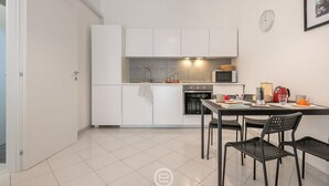 Eine moderne Küche mit weißen Schränken, einer Mikrowelle und einem Essbereich mit Tisch und Stühlen.