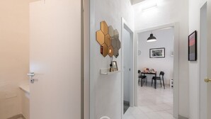 Ein Flur mit einem modernen, sechseckigen Wandbild, einem Essbereich mit Tisch und Stühlen sowie einer Tür zu einem weiteren Raum.