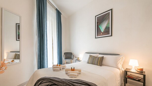 Ein Hotelzimmer mit einem großen Bett, einem Nachttisch mit Lampe, einem Sessel, einem Spiegel und einem Gemälde an der Wand.
