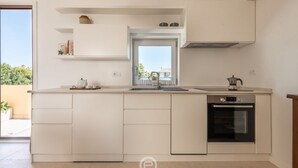 Una cocina moderna con horno empotrado, lavamanos y ventana sobre la encimera.