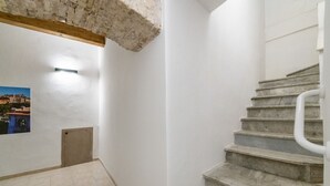 A staircase with stone steps leading to a landing, white walls, and a small door.
