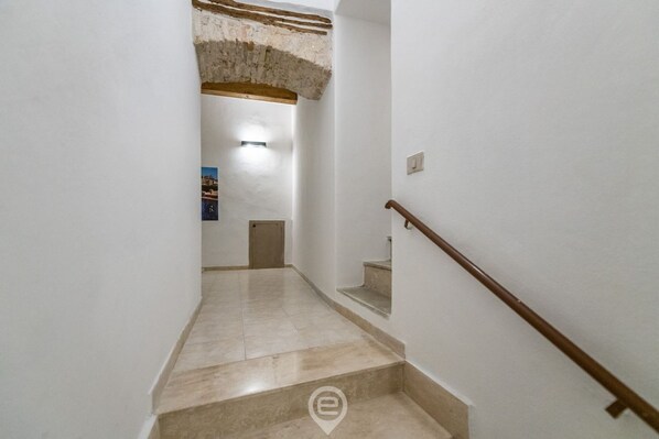A staircase with a wooden handrail leading to a landing with a light fixture.