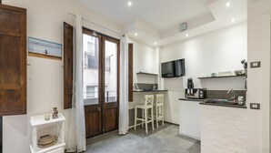 A modern kitchen with a TV, a coffee machine, and a small bar area.