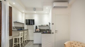 A compact kitchen with a TV, a coffee machine, and a small bar area.